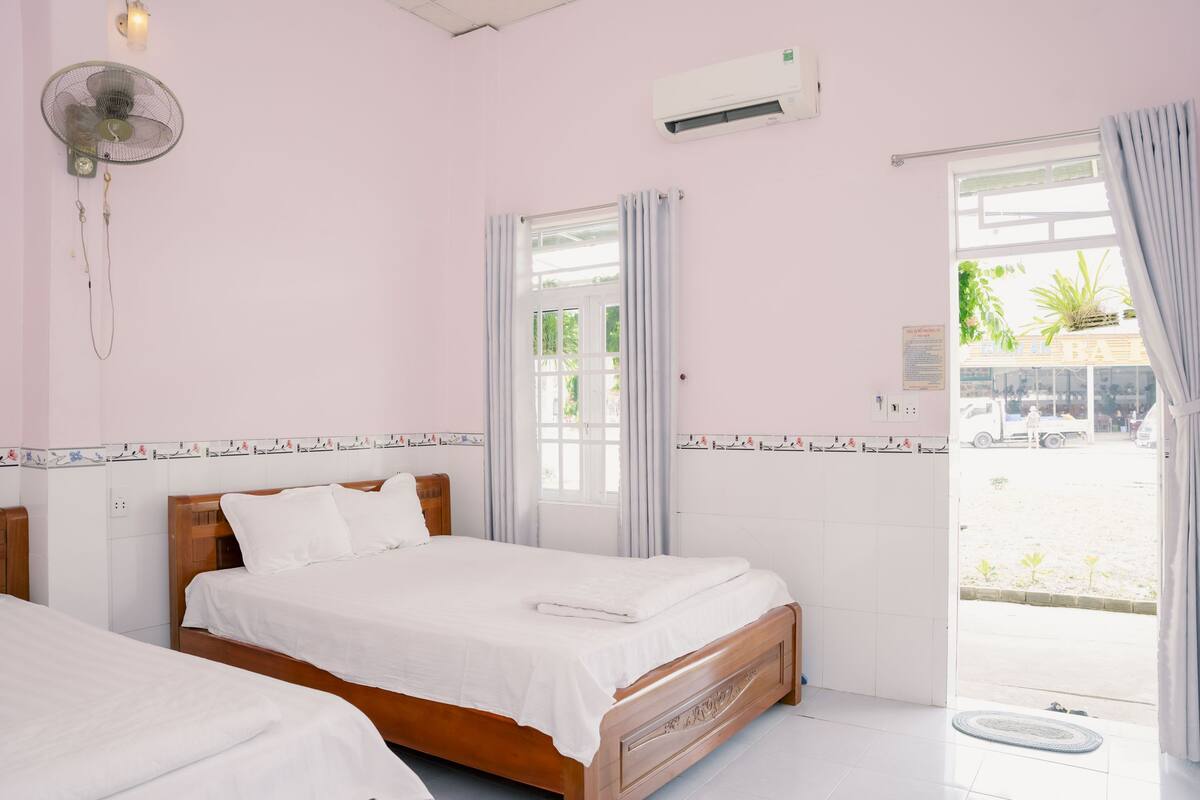 Une chambre avec deux lits, un ventilateur, un climatiseur et une vue sur l’extérieur.