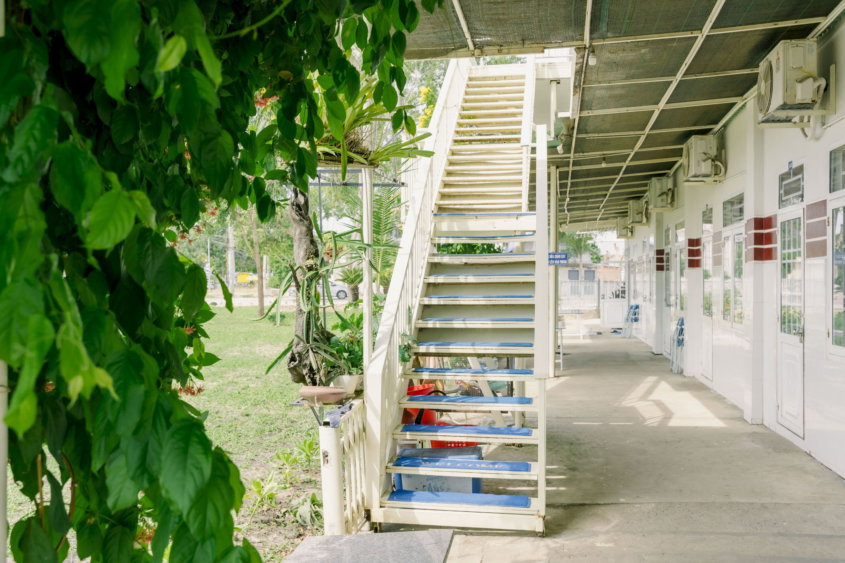 A covered outdoor staircase leading to a building with air conditioning units on the walls.