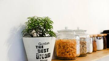 A potted plant in a white pot with the text "Garden The Best Dream Hope" on a wooden shelf.