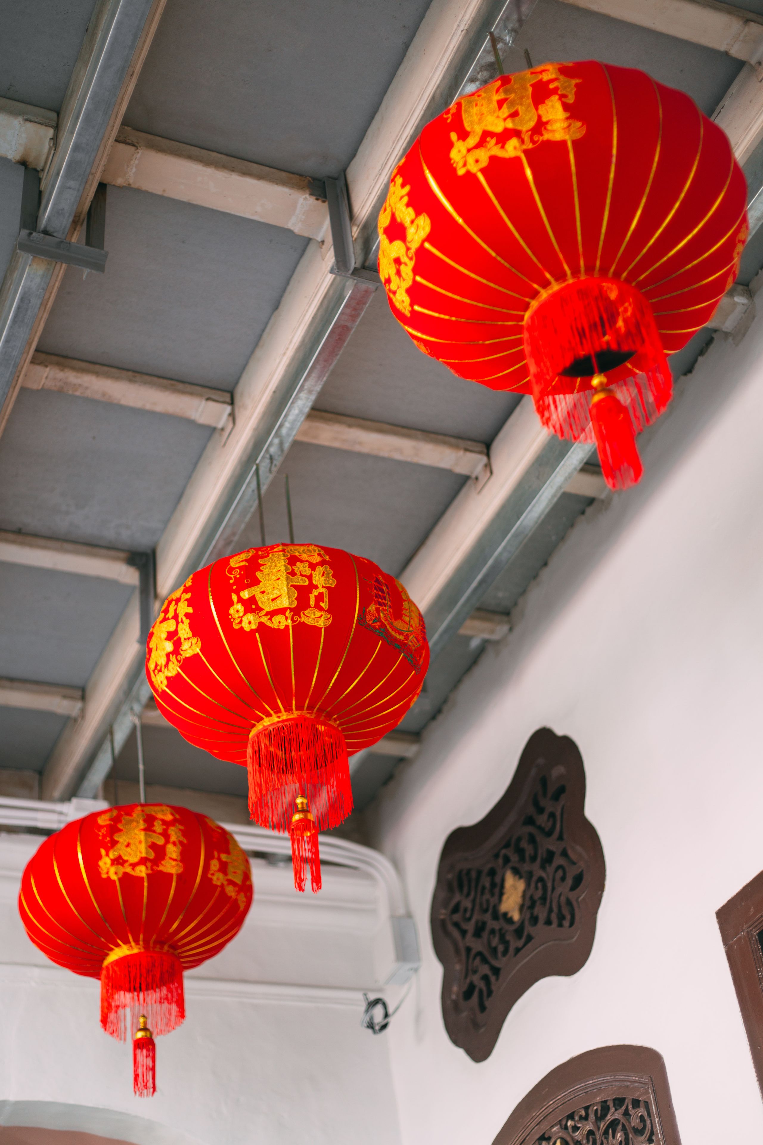 A ceiling with metal beams and red lanterns hanging from it.