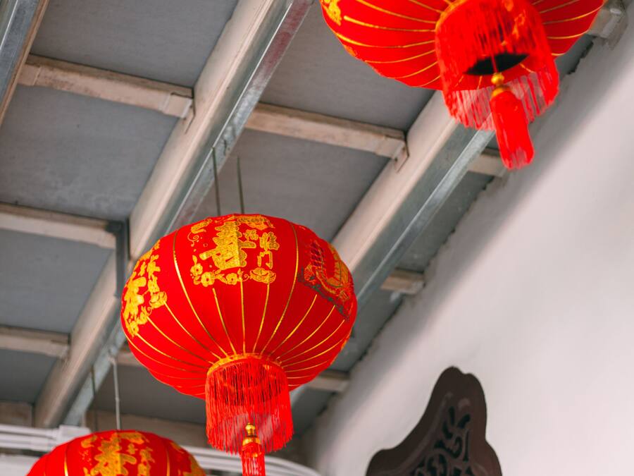 A ceiling with metal beams and red lanterns hanging from it.
