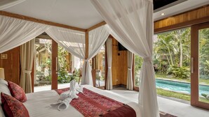 Un dormitorio espacioso con una cama grande, cortinas blancas y vistas a una piscina.