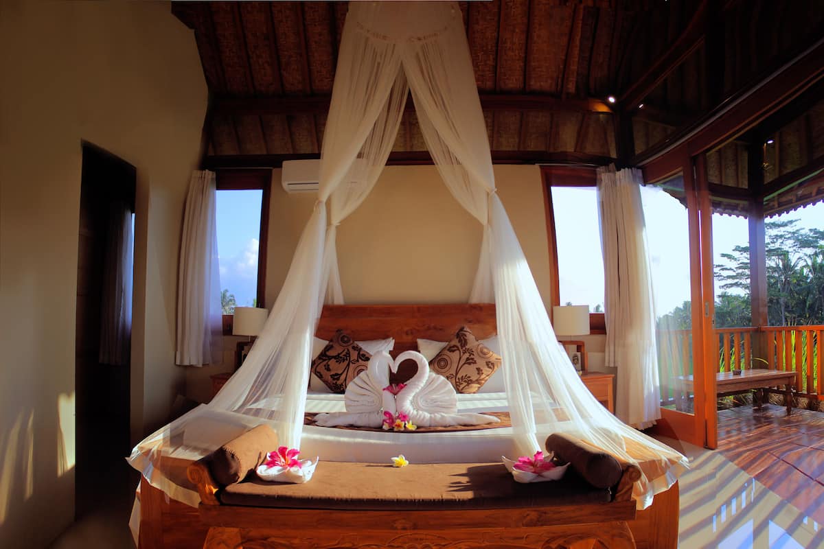 A bed with a canopy, pillows, and a wooden headboard.