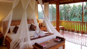 A bedroom with a canopy bed, a wooden bench, and a view of the garden. - Warisan Ubud Villa (Tegallalang)