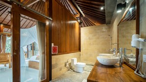 A bathroom with a wooden vanity, a large mirror, and a white sink. - Naja Private Villa (Ubud)