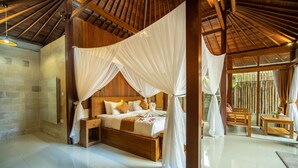 A spacious bedroom with a large bed, wooden headboard, and a canopy. - Naja Private Villa (Ubud)