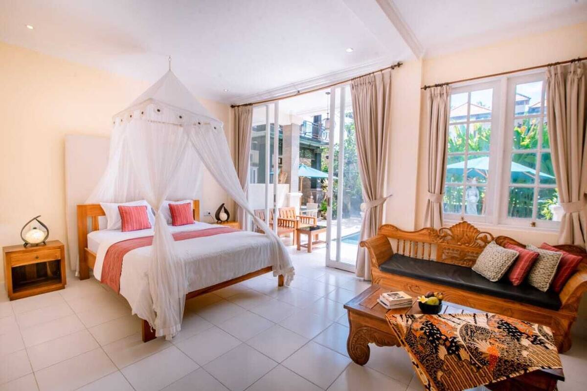 A bedroom with a canopy bed, a sofa, and a coffee table.