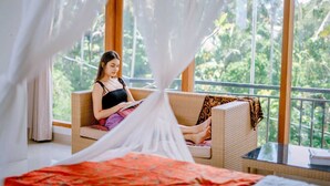 A room with a large window, a wicker sofa, and a bed with a red bedspread. - Sekembang Ubud Villa (Ubud)