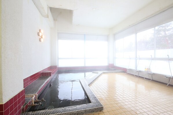 A large indoor pool with tiled walls and floor, clear windows, and visible plumbing. - Hotel Tagawa (Yamanouchi)