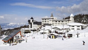 A snow-covered ski resort with buildings, including a lodge and a ski lift area. - Hotel Tagawa (Yamanouchi)