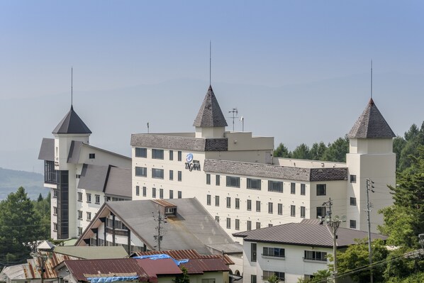 A multi-story hotel with a distinctive architectural design featuring two prominent towers with pointed roofs. - Hotel Tagawa (Yamanouchi)