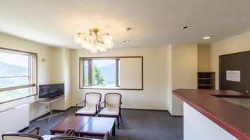 A conference room with a TV, chairs, a table, a reception desk, and a window with a view.
