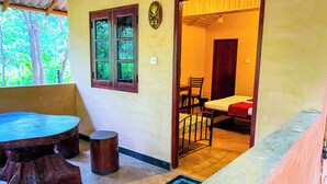 A room with a bed, a chair, a table, and a window with a view of trees. - Niyagala Lodge (Sigiriya)