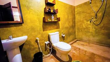 A bathroom with a toilet, sink, and shower. There are shelves above the toilet with toiletries.