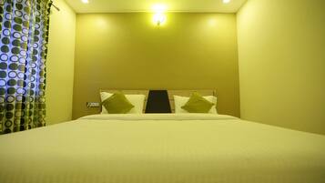 A hotel room with a bed, a headboard, and a wall-mounted light fixture.