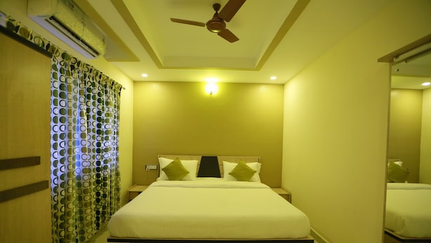 Une chambre d’hôtel équipée d’un lit, d’un ventilateur de plafond, d’un climatiseur et d’un miroir.