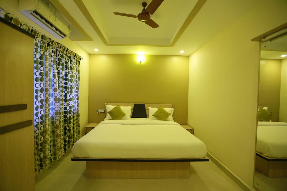 A hotel room with a bed, a ceiling fan, an air conditioning unit, and a mirror.