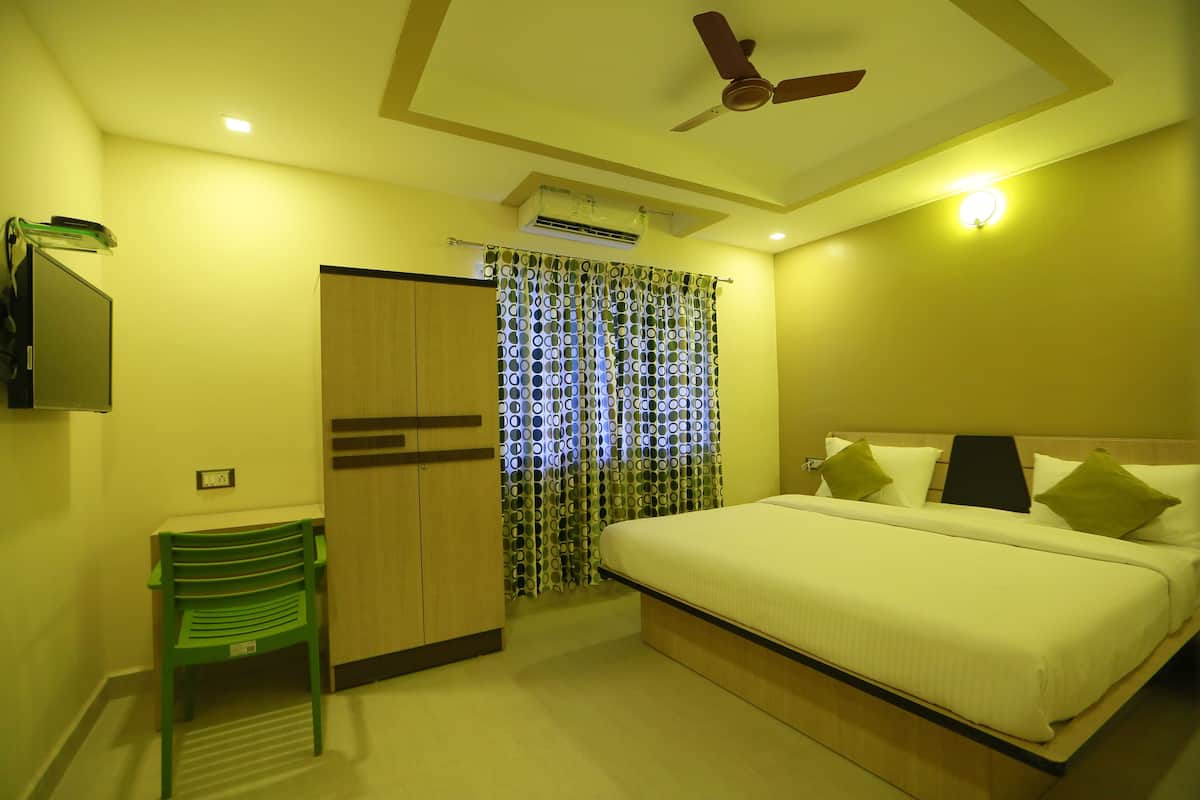 A hotel room with a bed, a desk, a chair, a ceiling fan, and a curtain with circular patterns.