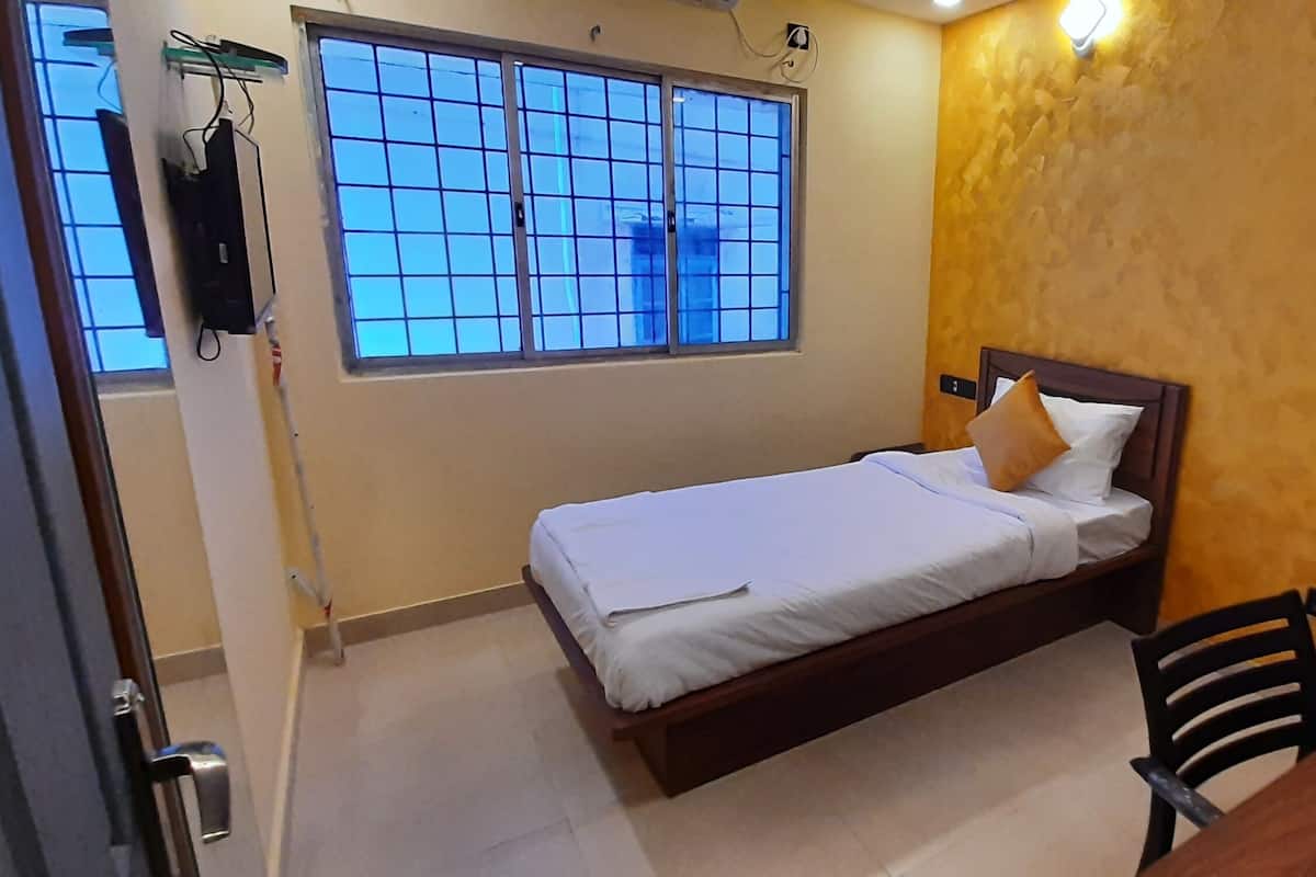 A small, neatly arranged bedroom with a single bed, a chair, and a desk.