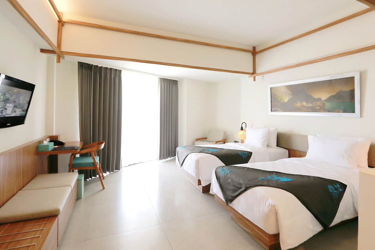 Een hotelkamer met twee bedden, een bureau met stoel, een televisie en een schilderij aan de muur.
