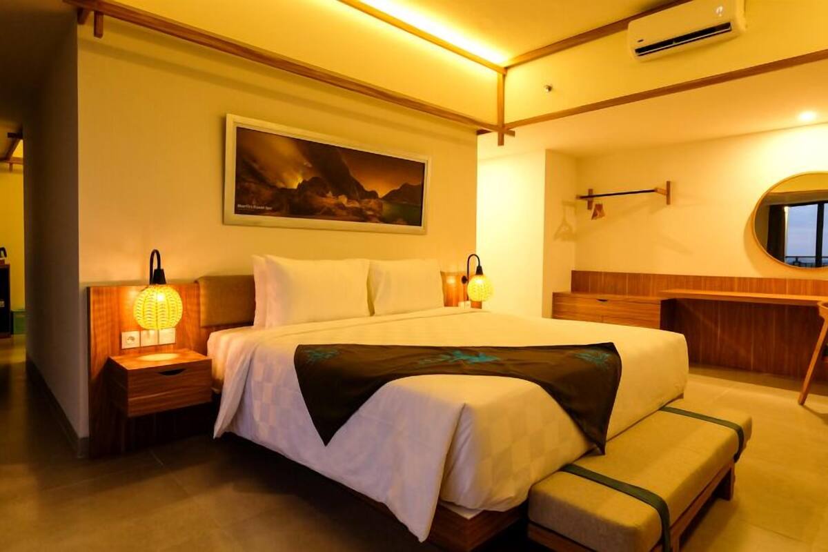 Een hotelkamer met een groot bed, bedlampen, een bureau en een stoel.