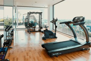Une salle de sport équipée de machines de cardio, de machines de musculation et d’haltères.