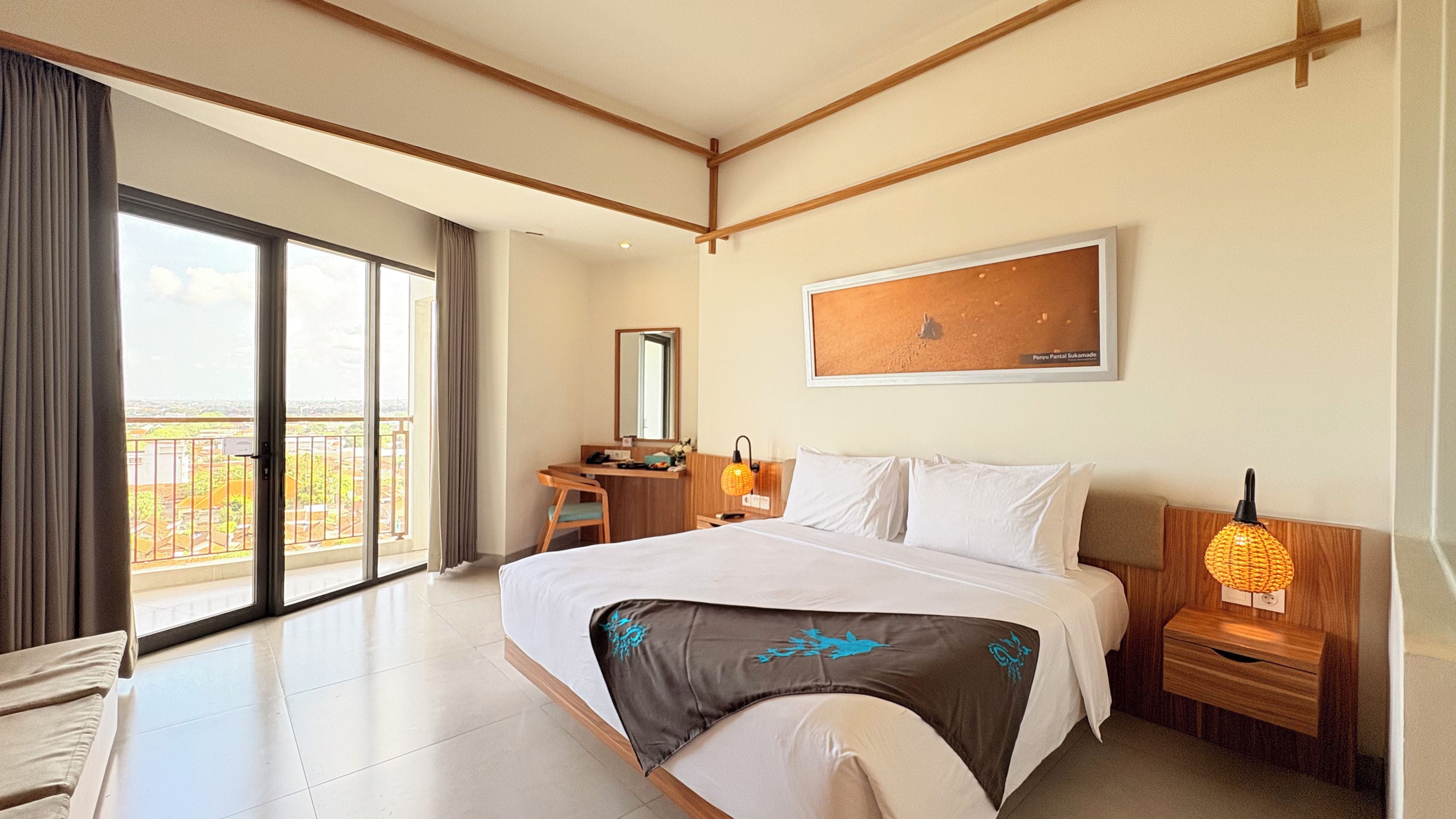 Habitación de hotel con una cama grande, un escritorio, una silla, una mesita de noche, una lámpara y vistas al exterior.