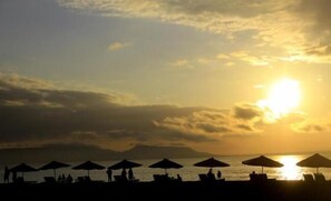 Une scène de plage avec des parasols et des chaises longues, évoquant un lieu de villégiature.