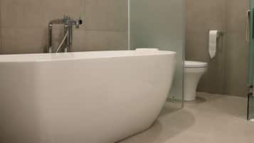 A modern bathroom with a freestanding bathtub, a toilet, and a glass shower enclosure.