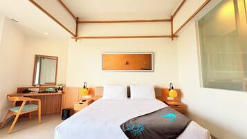 Een hotelkamer met een bed, nachtlampjes, een bureau met stoel, een spiegel en een lijst met een afbeelding aan de muur.