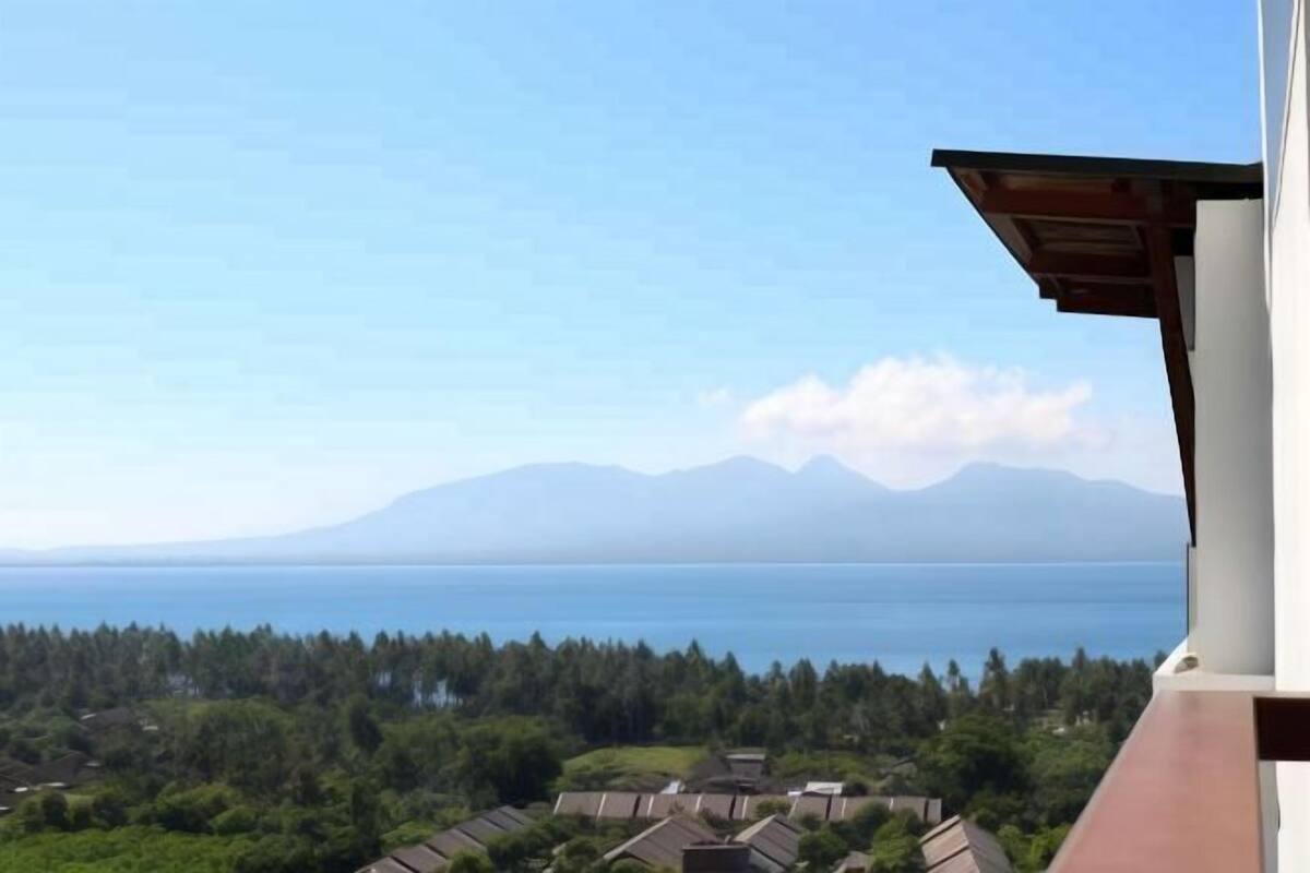 Enjoy breathtaking views of the serene lake and distant mountains from this high-rise's expansive balcony.