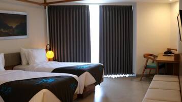 A hotel room with two beds, a desk, a chair, a TV, and a painting on the wall.