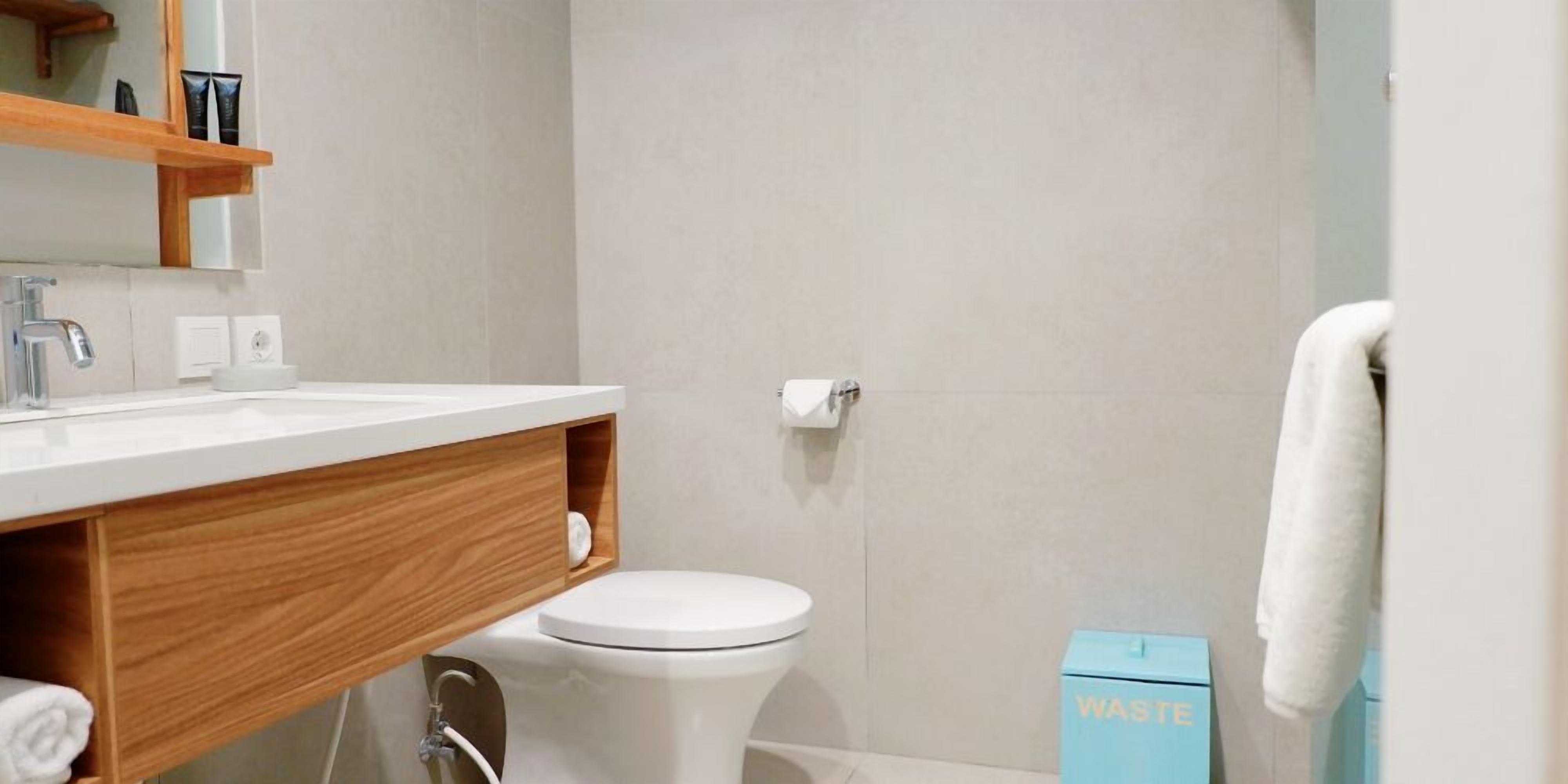 A modern bathroom with a white sink, wooden vanity, and a toilet.