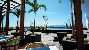 Un espace extérieur aménagé avec des tables et des chaises, entouré de plantes en pot et d’une piscine.
