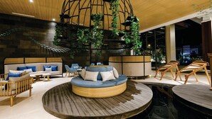 Un espace de détente moderne avec un aménagement circulaire des sièges, un plafond en bois et une grande installation végétale.