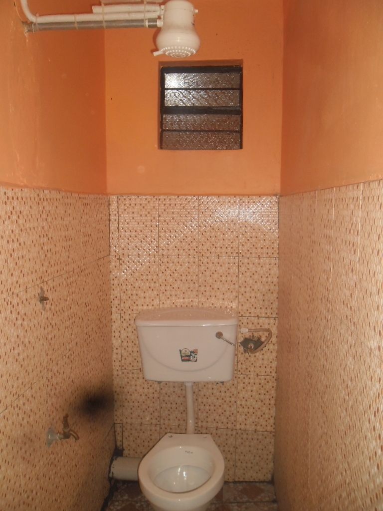 Uma casa de banho pequena e estreita, com sanita, uma pequena janela e paredes revestidas a azulejos.
