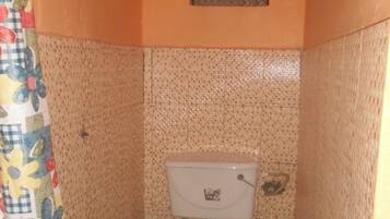 A small bathroom with a toilet, a shower curtain, and a window.