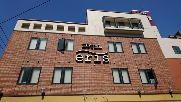 Ein Hotel namens 'Hotel Eris' mit einer modernen Ziegel-Fassade, zahlreichen Fenstern und einem sichtbaren Schild, das den Namen des Hotels zeigt.