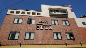 A hotel named 'Hotel Eris' with a modern brick facade, multiple windows, and a visible sign indicating the hotel's name.