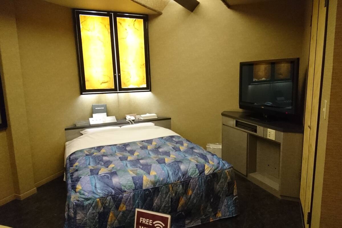 Ein Hotelzimmer mit Bett, Schreibtisch und Fernseher, sowie einem Schild für kostenloses WLAN.