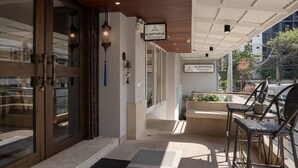 A hotel entrance with a wooden door, a sign for Aspira Residence, and outdoor seating with wicker chairs. - Aspira Residence Ruamrudee (Bangkok)