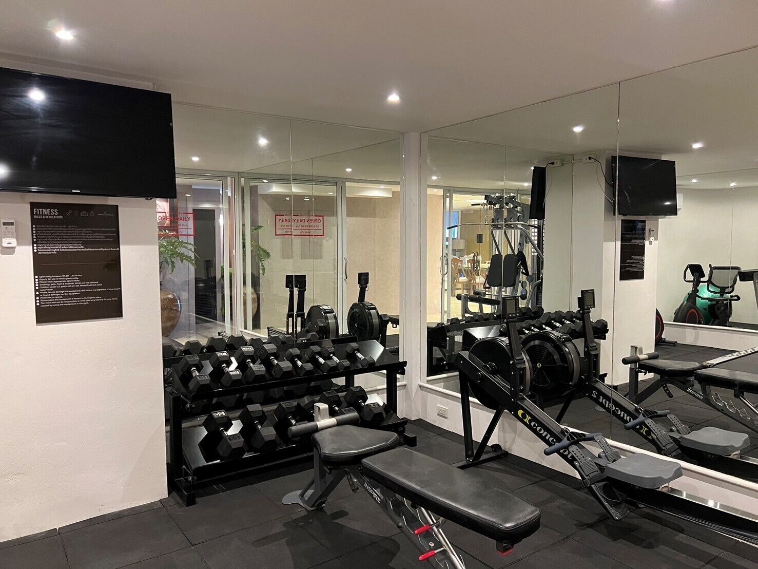A gym with weightlifting equipment, exercise machines, and a mirror wall.