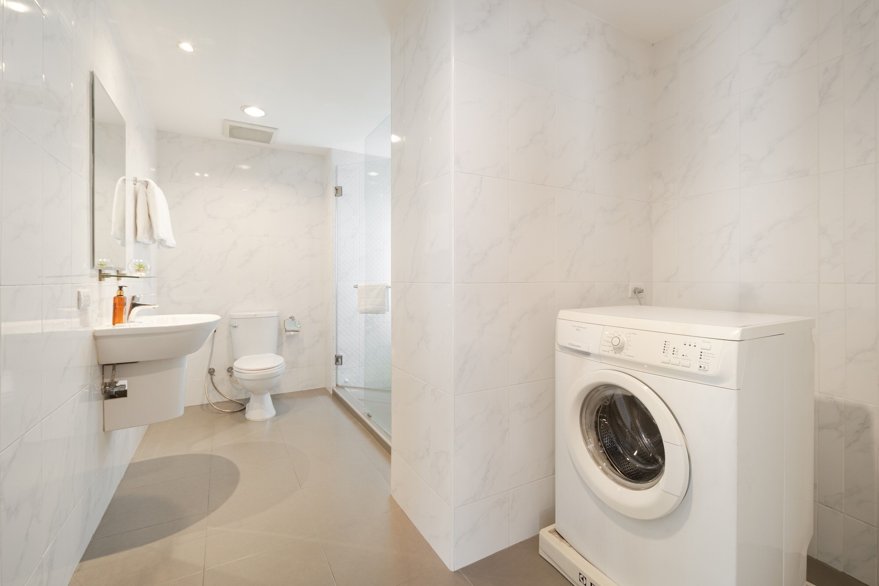 A modern bathroom with a sink, toilet, and washing machine.