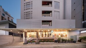A modern building with a curved facade, multiple balconies, and a covered entrance area with seating. - Aspira Residence Ruamrudee (Bangkok)