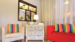 A living room with a white armchair, a red sofa, and a white cabinet with decorative items.