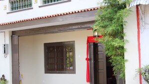 A building entrance with a closed door, a window with bars, and a red cloth hanging on the door.