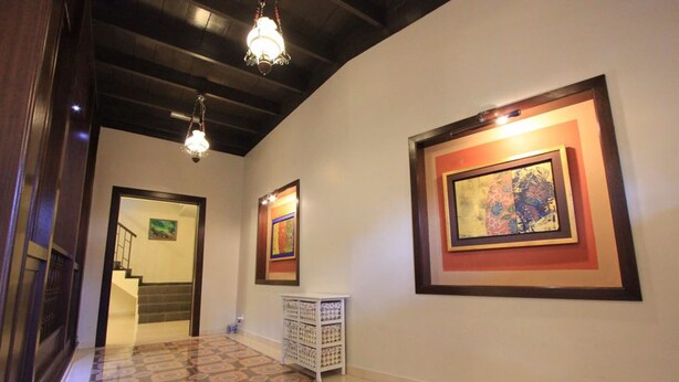 A hallway with patterned flooring, a staircase, and framed artwork on the walls.