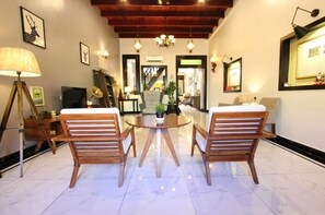 Amplia sala de estar con una mesa redonda de madera, dos sillas de madera, un candelabro y un televisor.