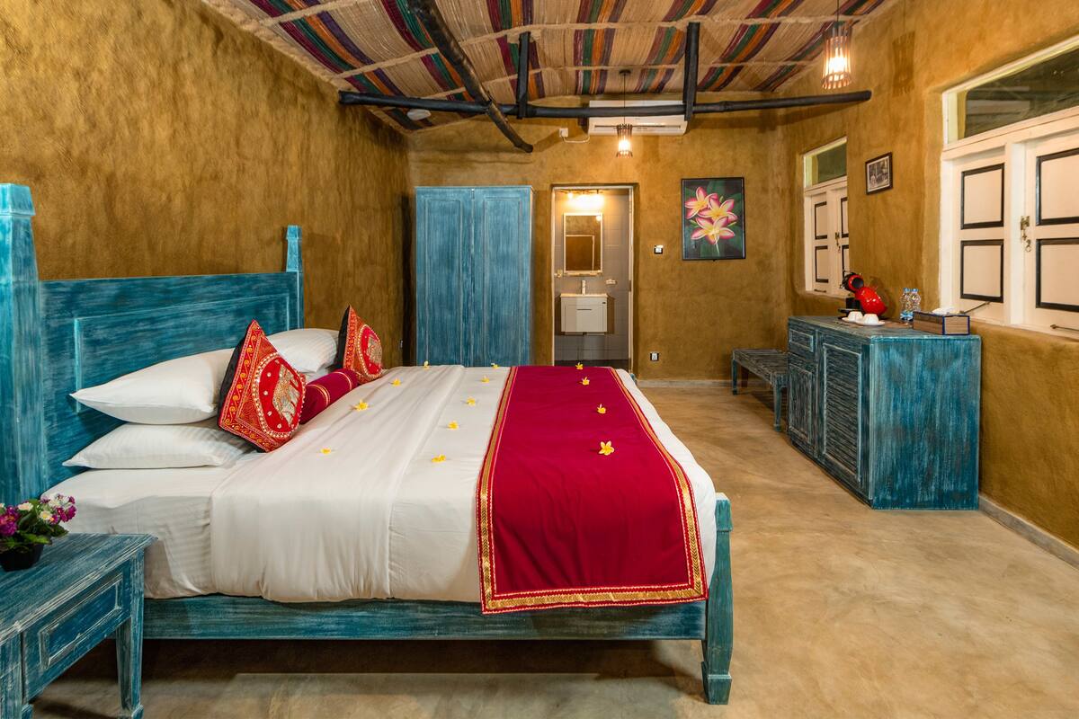Quarto com cama, mesas de cabeceira, cómoda e espelho.