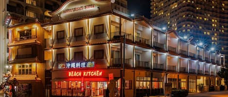 A multi-story hotel with a prominent 'Sunset Beach Hotel' sign and a 'Beach Kitchen' sign.